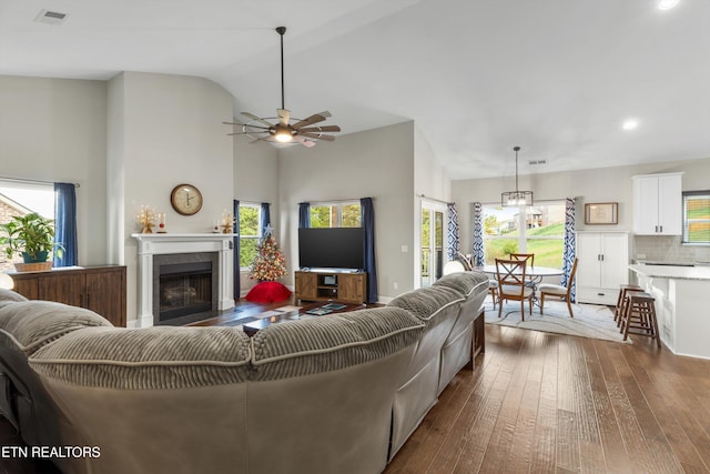 living room with dark wood-type flooring, ceiling fan, and high vaulted ceiling