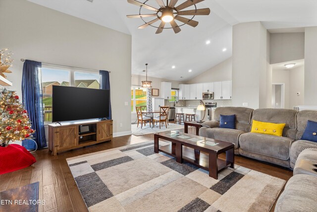 living room with hardwood / wood-style floors, ceiling fan, and high vaulted ceiling