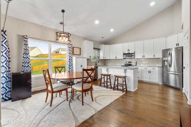 dining room featuring high vaulted ceiling, dark hardwood / wood-style flooring, a notable chandelier, and sink