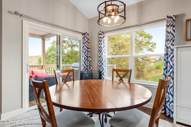 dining area featuring lofted ceiling, a healthy amount of sunlight, and an inviting chandelier