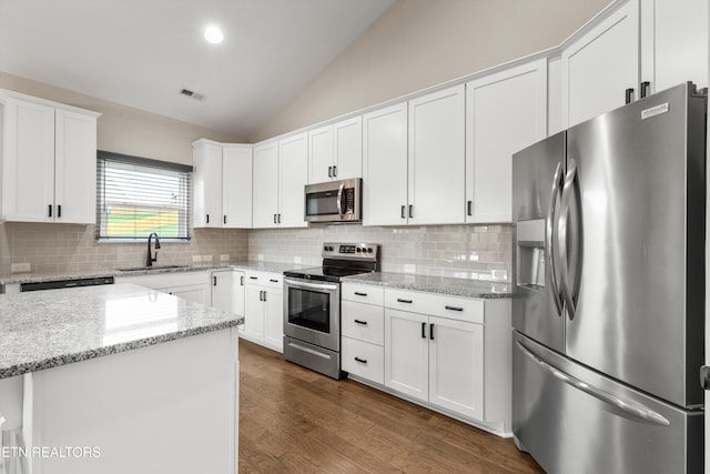 kitchen featuring white cabinets, stainless steel appliances, lofted ceiling, and dark hardwood / wood-style flooring