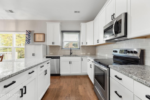 kitchen featuring stainless steel appliances, dark wood-type flooring, sink, light stone countertops, and white cabinetry