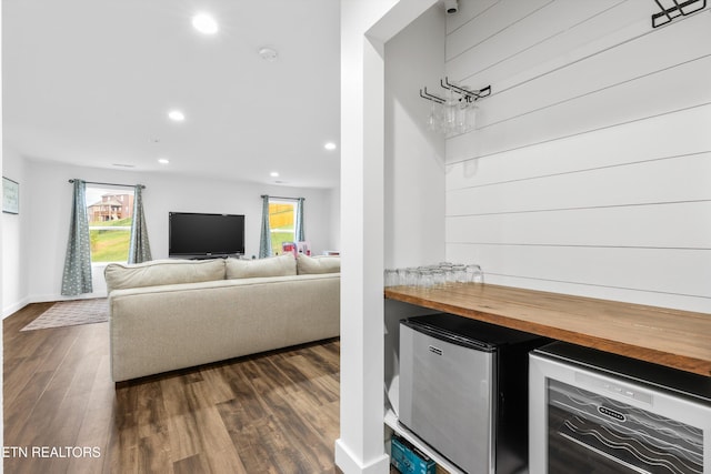 living room with dark wood-type flooring, a wealth of natural light, wine cooler, and indoor bar