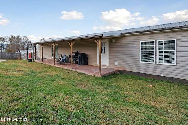 back of house with a patio and a lawn