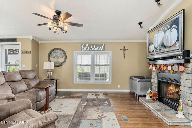 living room with ceiling fan, wood-type flooring, ornamental molding, and a fireplace