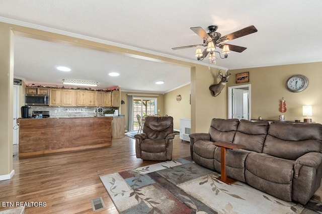 living room featuring light hardwood / wood-style floors, ceiling fan, and crown molding