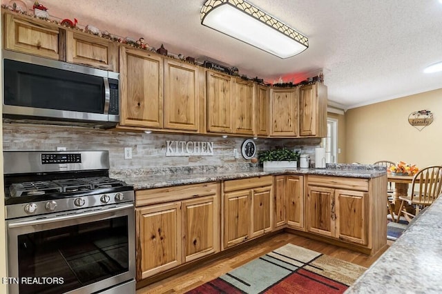 kitchen with backsplash, hardwood / wood-style floors, ornamental molding, and stainless steel appliances