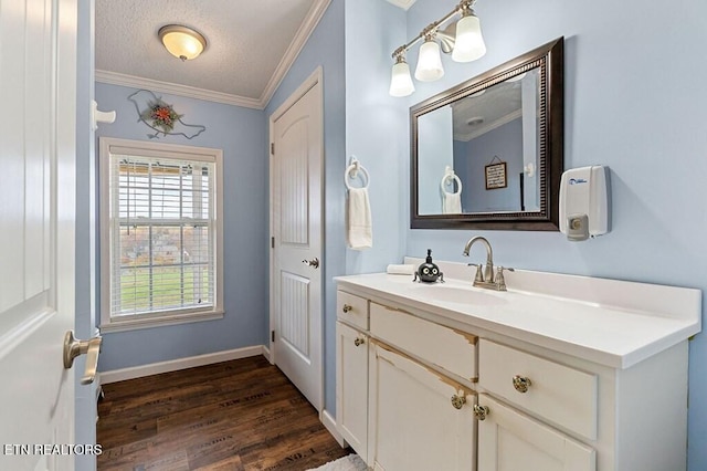 bathroom with vanity, hardwood / wood-style flooring, a textured ceiling, and crown molding