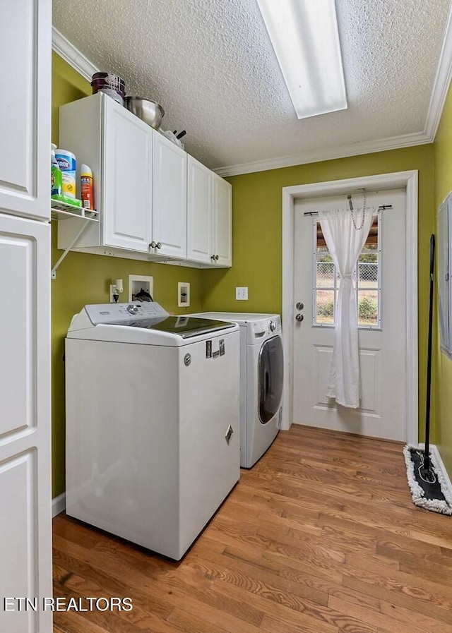 clothes washing area with crown molding, a textured ceiling, cabinets, light hardwood / wood-style floors, and independent washer and dryer