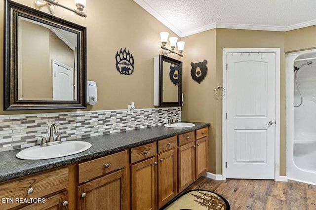 bathroom featuring hardwood / wood-style flooring, a textured ceiling, backsplash, vanity, and crown molding