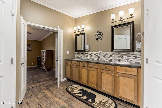 bathroom featuring crown molding, vanity, a textured ceiling, decorative backsplash, and hardwood / wood-style floors