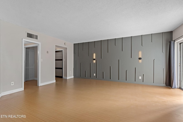 empty room featuring light wood-type flooring and a textured ceiling