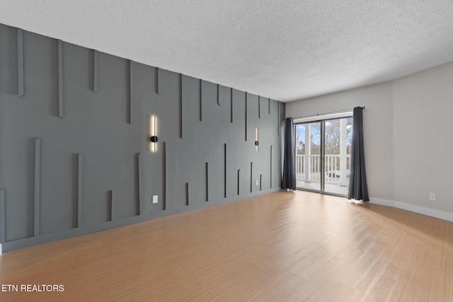 empty room with light hardwood / wood-style floors and a textured ceiling