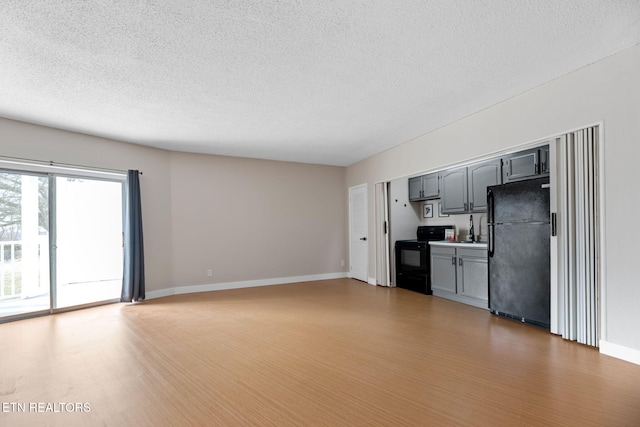 unfurnished living room with wood-type flooring and a textured ceiling