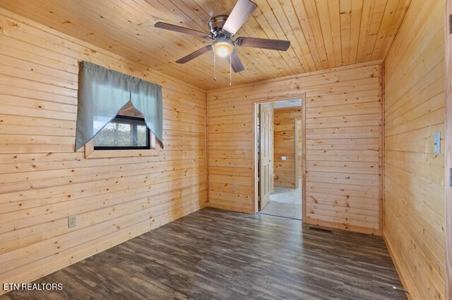 empty room featuring wooden walls, dark hardwood / wood-style floors, and ceiling fan