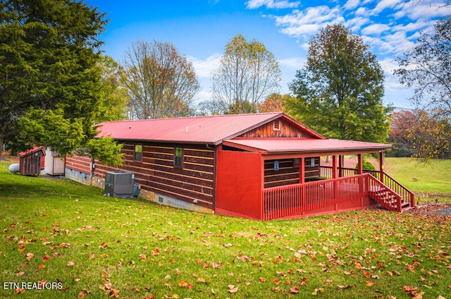 back of house with cooling unit, a lawn, and an outbuilding