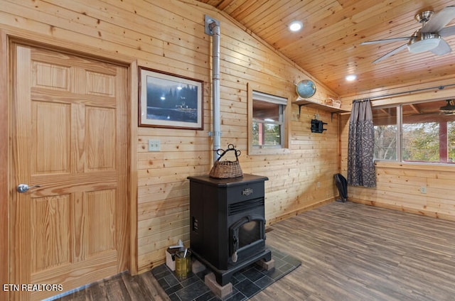 room details featuring a wood stove, wood walls, wood ceiling, hardwood / wood-style flooring, and ceiling fan