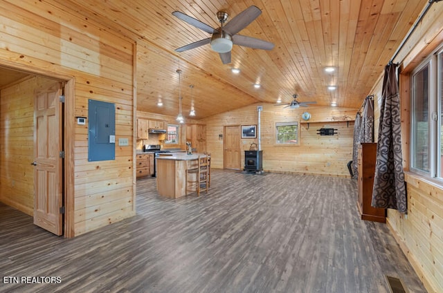 interior space with wood walls, a wood stove, lofted ceiling, a center island, and dark hardwood / wood-style flooring