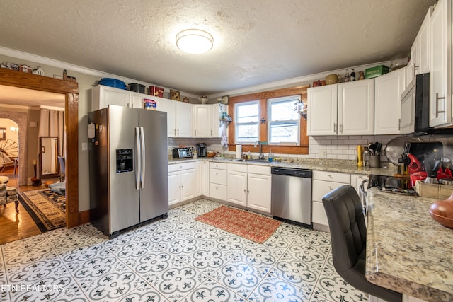 kitchen with ornamental molding, appliances with stainless steel finishes, white cabinets, and sink