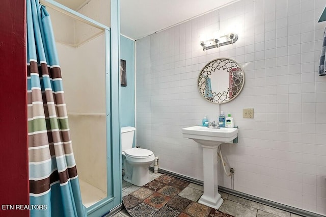 bathroom featuring a shower with curtain, toilet, tile walls, and sink