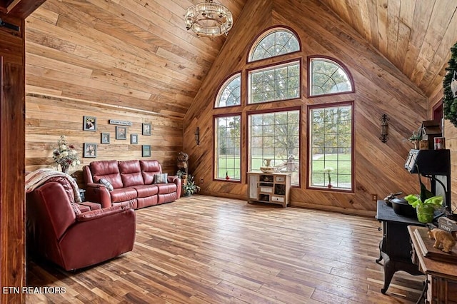 living room featuring high vaulted ceiling, a wealth of natural light, wood-type flooring, and wooden walls