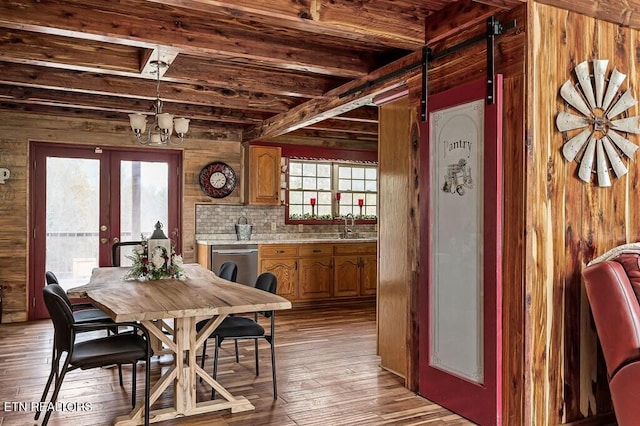 dining space featuring light hardwood / wood-style floors, wooden walls, french doors, and a healthy amount of sunlight