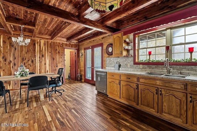 kitchen featuring wooden walls, sink, an inviting chandelier, decorative backsplash, and dark wood-type flooring