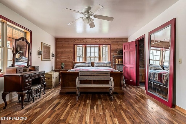 bedroom with wood walls, dark hardwood / wood-style floors, and ceiling fan