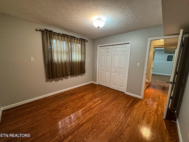 unfurnished bedroom featuring dark wood-type flooring, a textured ceiling, and a closet