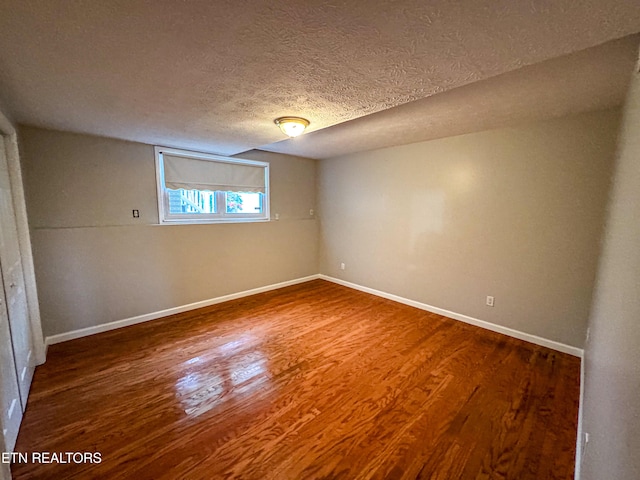 empty room with dark wood-type flooring and a textured ceiling