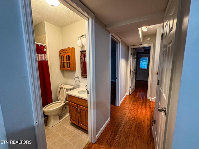 bathroom with wood-type flooring, toilet, curtained shower, a textured ceiling, and vanity