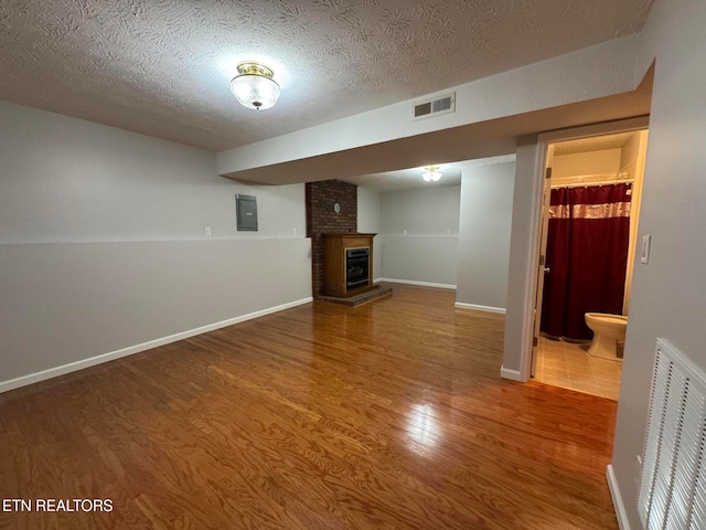 unfurnished living room with electric panel, wood-type flooring, and a textured ceiling