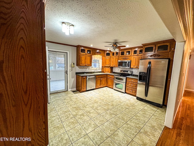 kitchen featuring stainless steel appliances, sink, ornamental molding, light tile patterned floors, and decorative backsplash