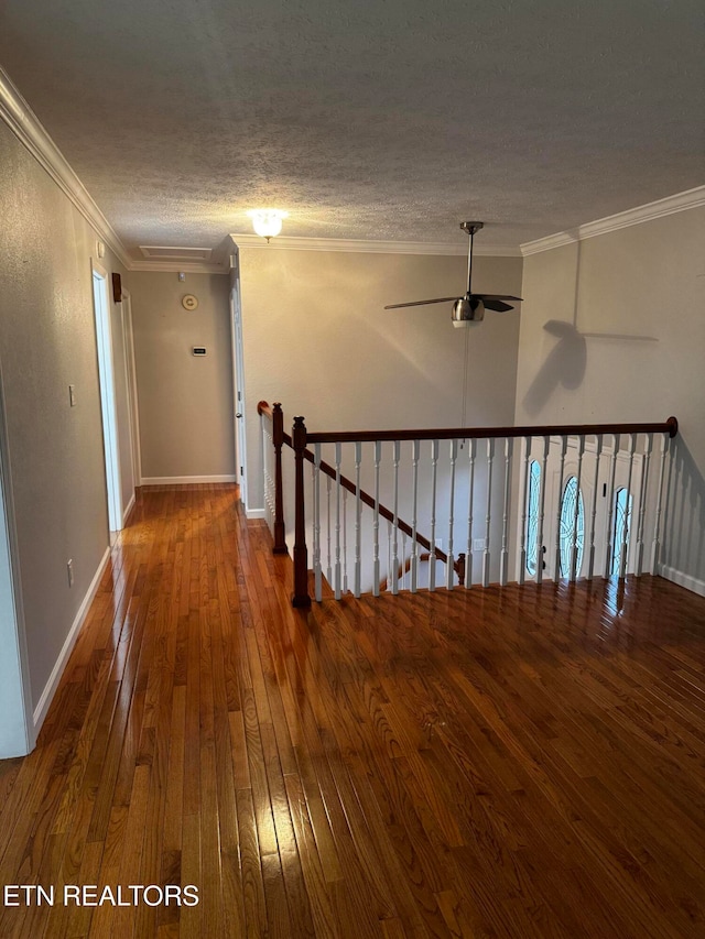 hallway with wood-type flooring, a textured ceiling, and ornamental molding