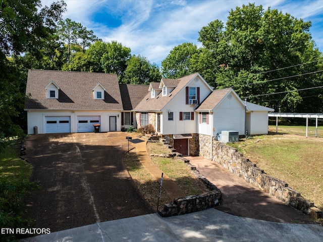 new england style home with central AC unit, a front yard, a garage, and a carport