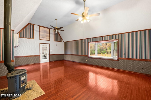 unfurnished living room featuring hardwood / wood-style floors, ceiling fan, a wood stove, and high vaulted ceiling