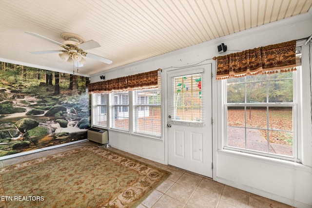 unfurnished sunroom with a wall mounted AC, a healthy amount of sunlight, and ceiling fan