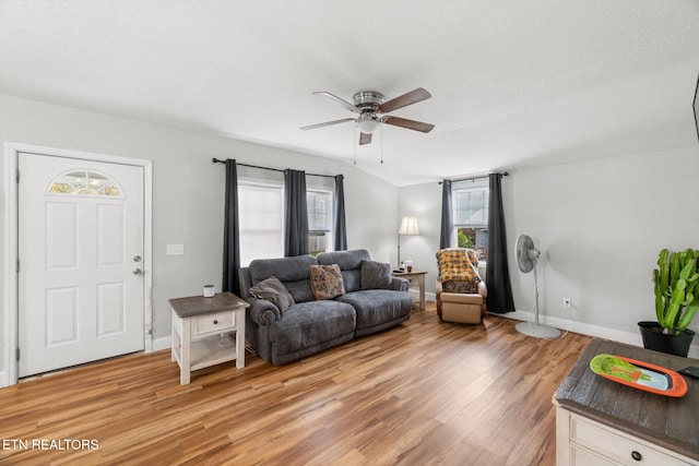 living room with hardwood / wood-style flooring, ceiling fan, lofted ceiling, and a textured ceiling