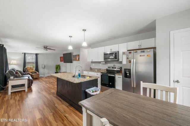 kitchen featuring appliances with stainless steel finishes, ceiling fan, sink, a center island with sink, and white cabinetry