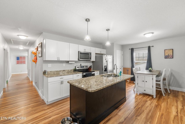 kitchen featuring sink, stainless steel appliances, pendant lighting, white cabinets, and light wood-type flooring