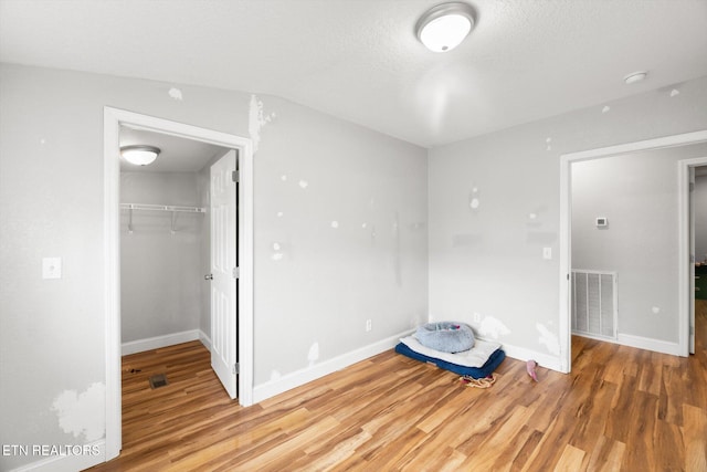 unfurnished bedroom featuring hardwood / wood-style floors, a textured ceiling, and a closet