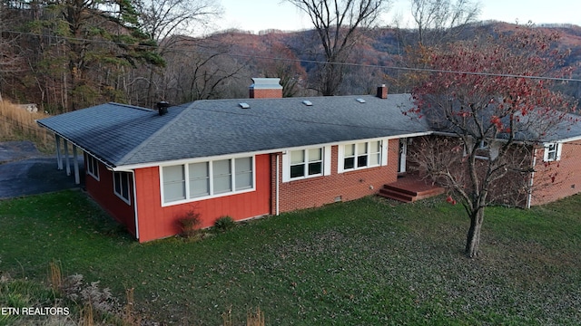 rear view of house with a mountain view and a yard