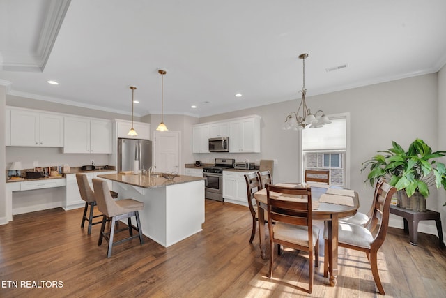 kitchen with white cabinets, appliances with stainless steel finishes, a center island with sink, and dark hardwood / wood-style flooring