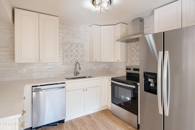 kitchen with stainless steel appliances, wall chimney range hood, decorative backsplash, sink, and light hardwood / wood-style floors