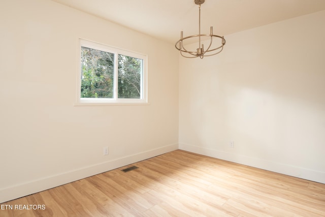 unfurnished room featuring light hardwood / wood-style floors and a chandelier