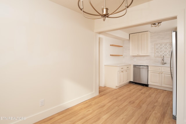 kitchen featuring light hardwood / wood-style floors, appliances with stainless steel finishes, decorative light fixtures, a chandelier, and decorative backsplash