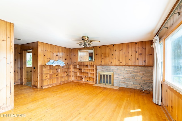 unfurnished living room with hardwood / wood-style floors, wood walls, and a healthy amount of sunlight