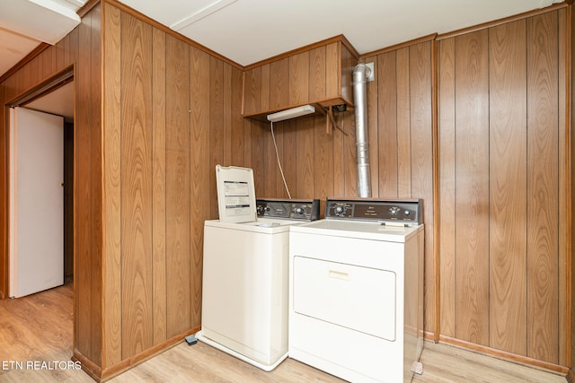 laundry room with wood walls, light wood-type flooring, and independent washer and dryer