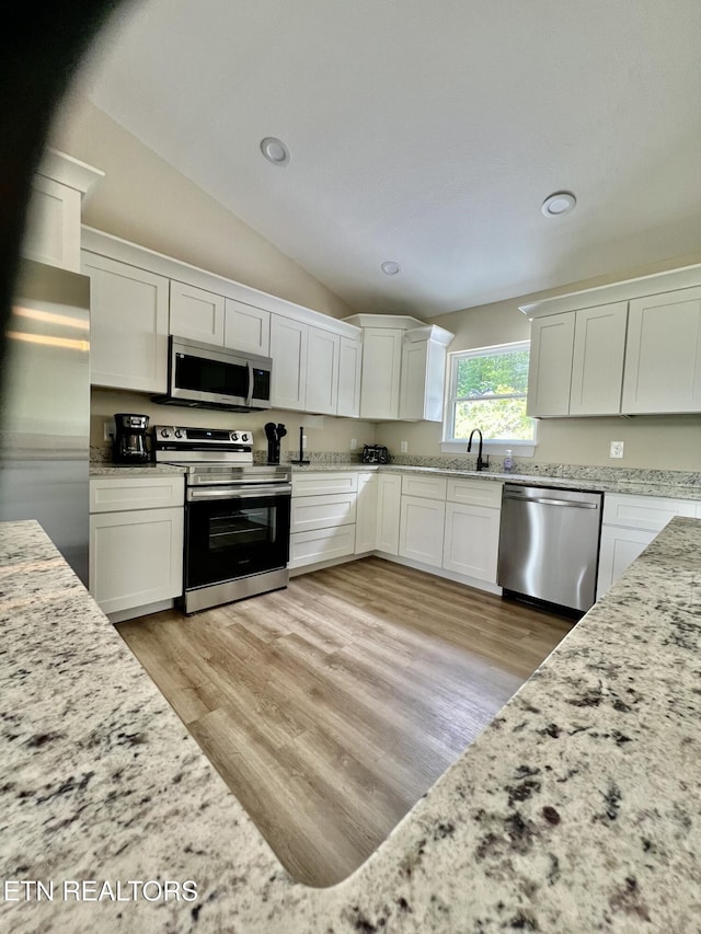 139 Pool Rd, Lafollette, TN 37766 - kitchen featuring stainless steel appliances, white cabinets, vaulted ceiling, light stone countertops, and light wood-type flooring