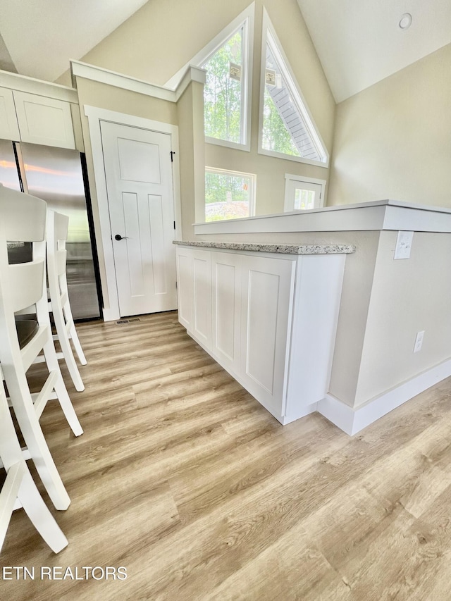139 Pool Rd, Lafollette, TN 37766 - kitchen featuring light wood-style flooring, white cabinets, vaulted ceiling, fridge, and light stone countertops